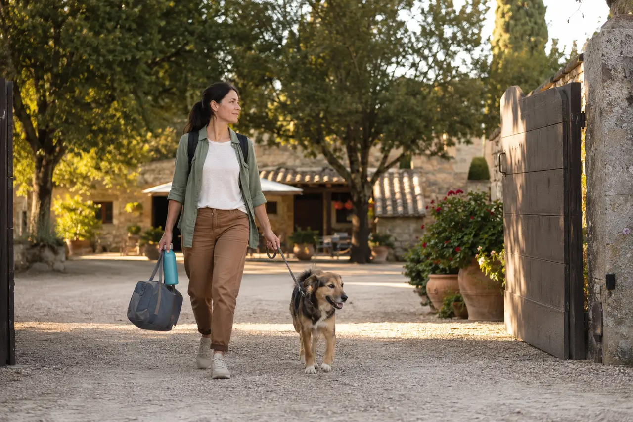 Proprietaria arriva con il cane al guinzaglio in una struttura ricettiva di campagna